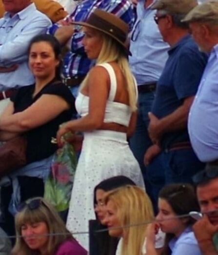 Luciana Abreu de vestido branco e chapéu castanho, em pé, a aplaudir o namorado.
