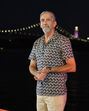Homem posa com a Ponte 25 de Abril iluminada ao fundo