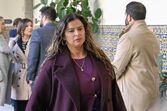 Mulher com casaco roxo num evento com outras pessoas