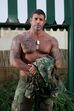 Homem exibe forma física e tatuagens com vestuário militar