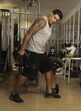 Homem faz exercício de elevação lateral com haltere numa academia
