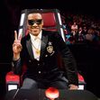 Homem sorri com óculos de sol e fato numa cadeira do The Voice