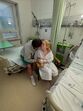 Homem beija mulher num quarto de hospital, demonstrando apoio e carinho