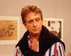 O ator David McCallum surge com um olhar pensativo e uma camisa às riscas