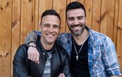 Dois homens sorriem lado a lado para a câmara