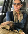 Pessoa com óculos de sol, colar dourado e mala Gucci
