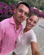 Um casal sorri para a câmara num cenário florido e soalheiro