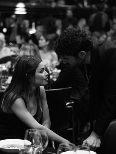 Dois convidados conversam num evento, em ambiente formal