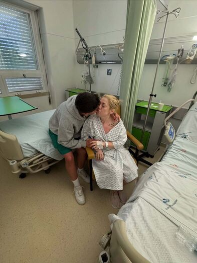 Homem beija mulher num quarto de hospital, demonstrando apoio e carinho
