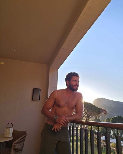 Homem sem camisa relaxa na varanda com vista para a montanha