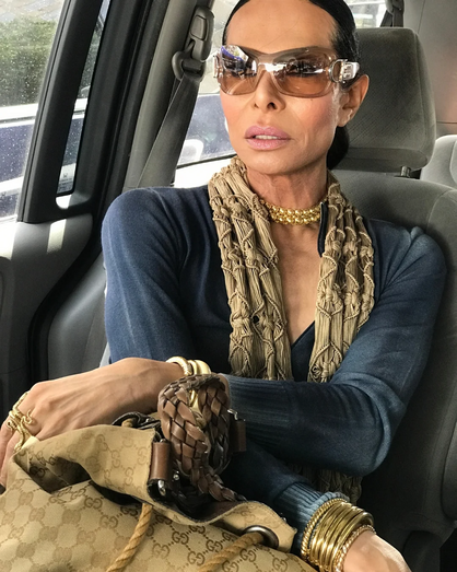 Pessoa com óculos de sol, colar dourado e mala Gucci