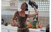 Mulher posa com vestido estampado, colar e mala preta
