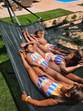 Crianças relaxam numa rede com fatos de banho coloridos num dia de sol