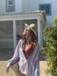 Mulher de chapéu, óculos de sol e camisa listrada aproveita o sol