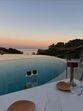 Mesa de refeições com vista para a piscina e o mar ao pôr do sol