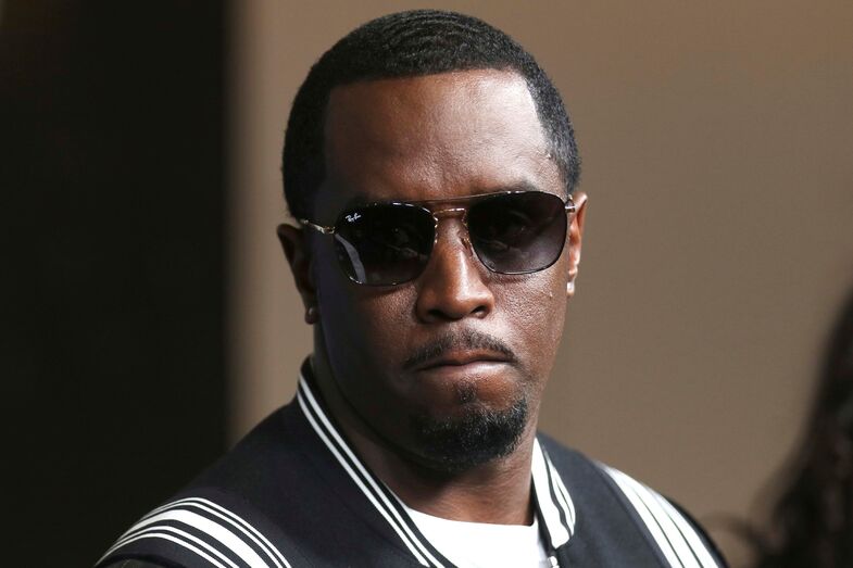Diddy usa óculos de sol e casaco preto com riscas brancas