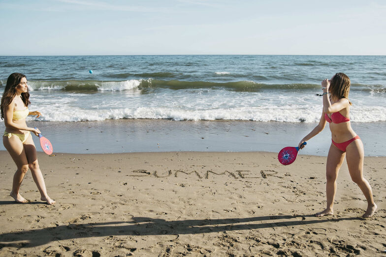 Praia, raquetes e a palavra "Summer" na areia: verão com descontração