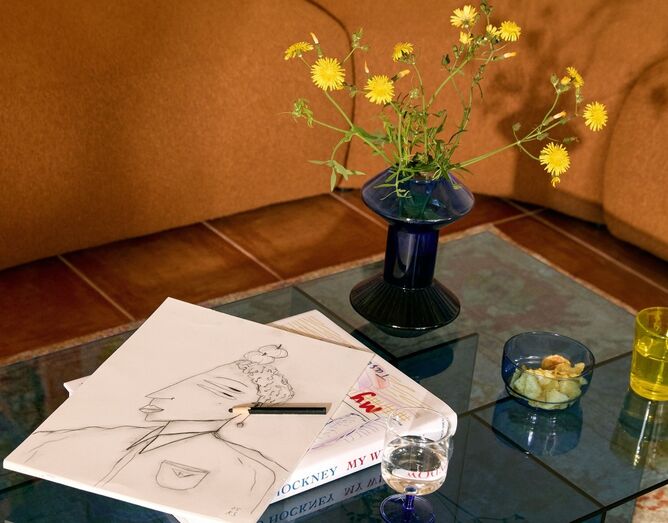 Decoração de interiores com jarra, desenho e livro de David Hockney.
