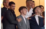 Várias pessoas assistem a um evento, com atenção focada num ponto em comum