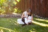 Menina abraça o seu gato num jardim ensolarado