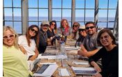 Grupo de pessoas reunidas à mesa num espaço com vista para o mar
