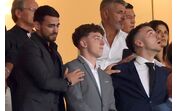 Várias pessoas assistem a um evento, com atenção focada num ponto em comum