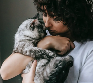 Mulher abraça gato com carinho.
