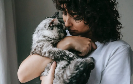 Mulher abraça gato com carinho.