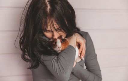 Mulher demonstra afeto por um porquinho-da-índia, realçando a ternura dos animais de estimação em espaços pequenos