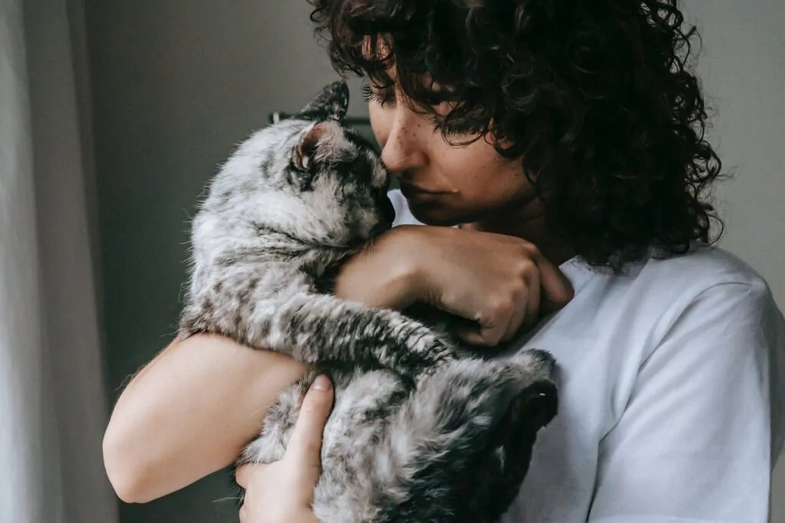 Mulher abraça gato com carinho.