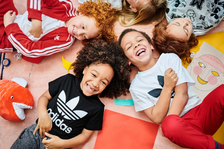 Crianças sorridentes vestem Adidas para o regresso às aulas com desconto