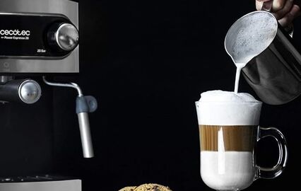 Máquina de café prepara bebida com leite e espuma perto de biscoitos