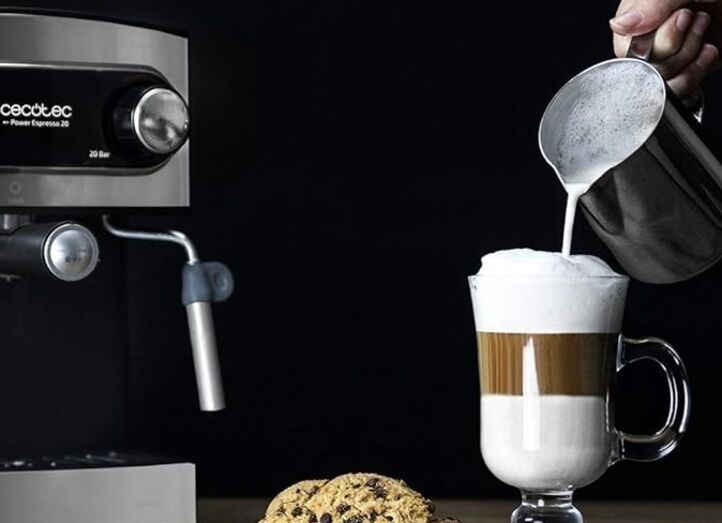 Máquina de café prepara bebida com leite e espuma perto de biscoitos