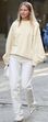 Mulher com visual monocromático branco, incluindo calças de ganga e camisola bege