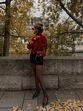 Mulher com camisola vermelha e minissaia em Paris, com árvores de outono