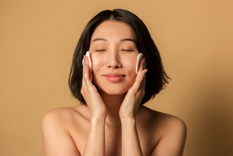 Mulher asiática limpa a pele do rosto com algodão para uma rotina de beleza