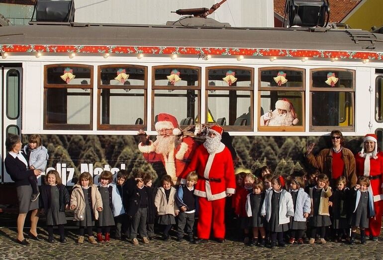 Elétrico de Natal com Pai Natal e crianças para uma viagem solidária