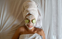 Bem-estar em foco: mulher relaxa com máscara facial e pepinos