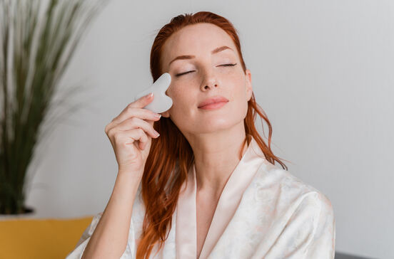 Mulher usa creme facial para hidratar e acabar com a pele baça