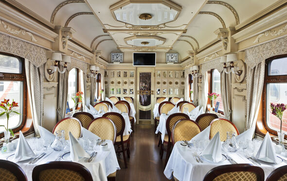 Interior de comboio de luxo, com mesas postas e decoração clássica