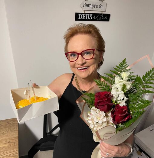 Noémia Costa celebra com bolo e flores após cirurgia metabólica.
