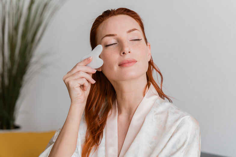 Mulher usa creme facial para hidratar e acabar com a pele baça