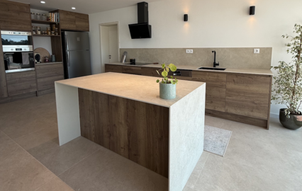 Cozinha remodelada com ilha central, armários em madeira e toques de modernidade