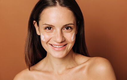 Mulher aplica creme facial para iluminar e aperfeiçoar o rosto