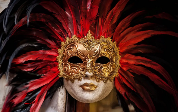 Máscara veneziana dourada com penas vermelhas e pretas no Carnaval de Lisboa