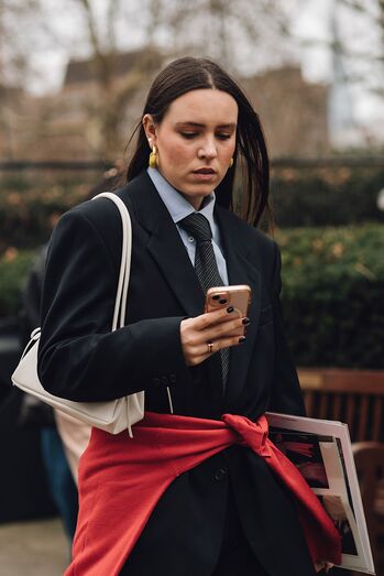 Tendências da primavera: mulher com blazer e gravata consulta o telemóvel