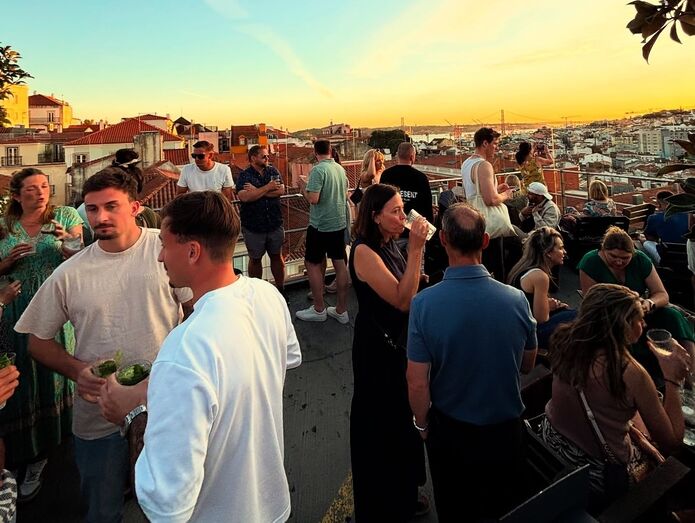 Pessoas aproveitam o sol numa esplanada em Lisboa com vista sobre a cidade