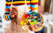 Uma pessoa segura numa paleta de cores e pincel, pronta para pintar