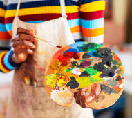 Uma pessoa segura numa paleta de cores e pincel, pronta para pintar