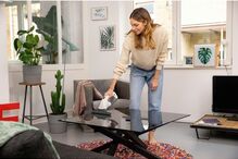 Mulher limpa mesa de vidro com utensílio para vidros impecáveis